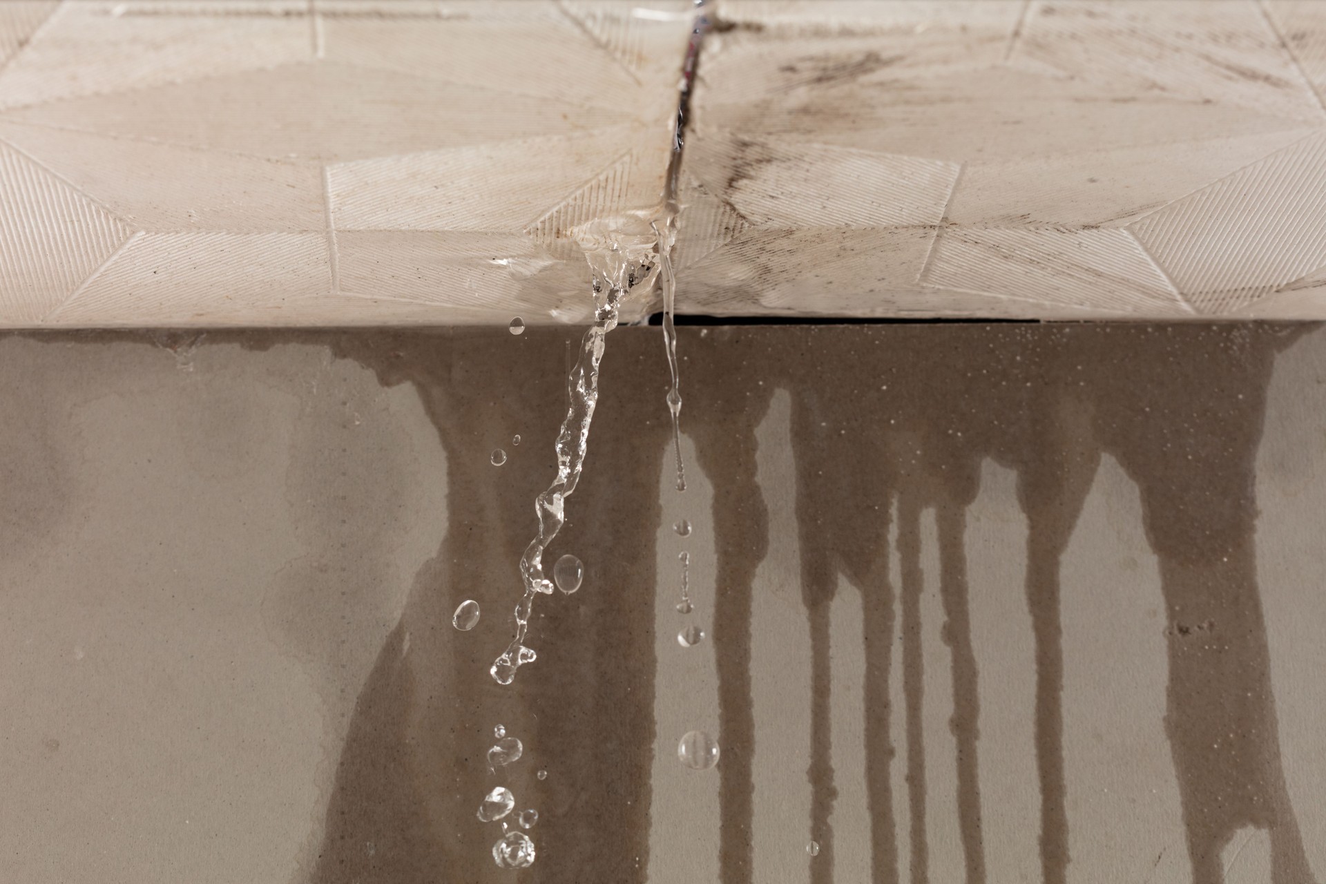 Heavy storm rain create water flow from edge of ceiling and dirty stain on wall. Water leaking from top ceiling as droplets and flow in old house